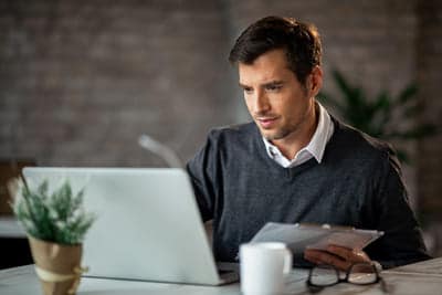 mid adult businessman entering data from business reports computer office 1 1 Clases de alemán online